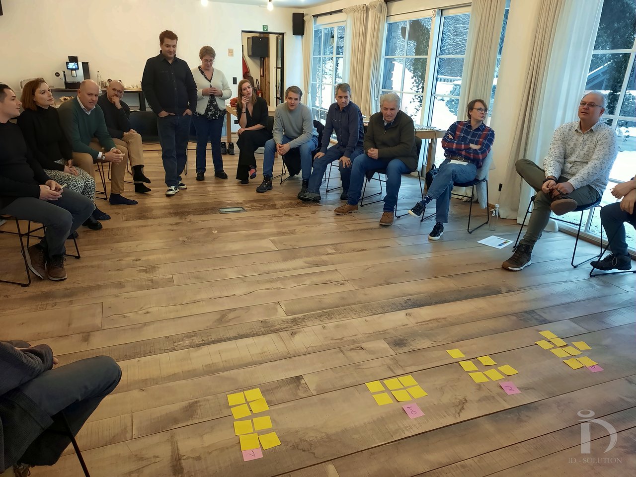 Un grand cercle de participants réunis autour de post-its posés au sol