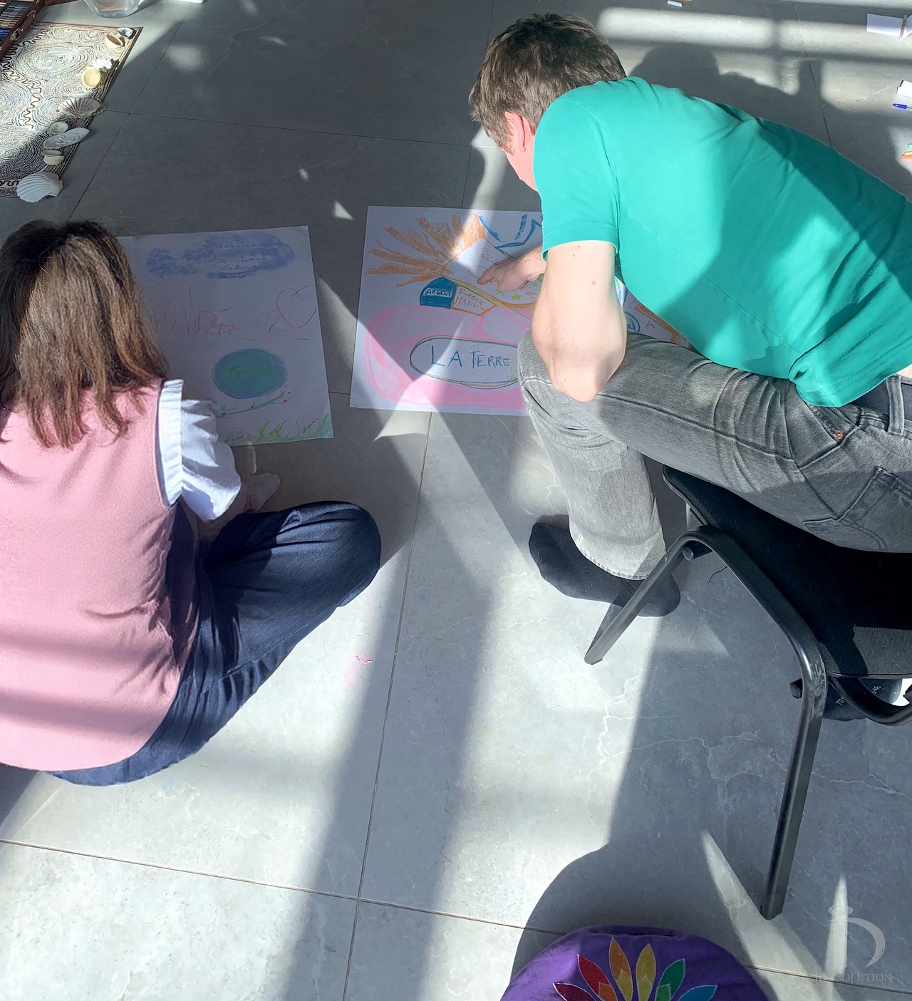 Deux participants échangent autour de leurs dessins posés au sol